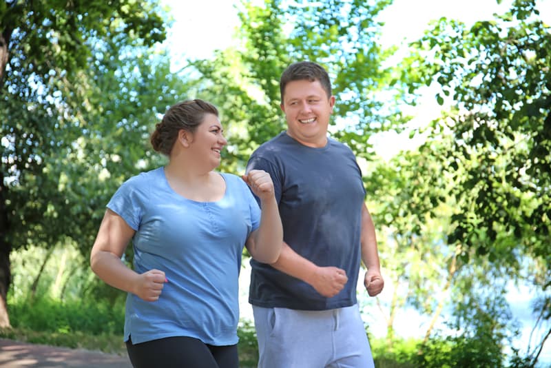 An overweight couple going for a run in the park as part of their weight loss journey