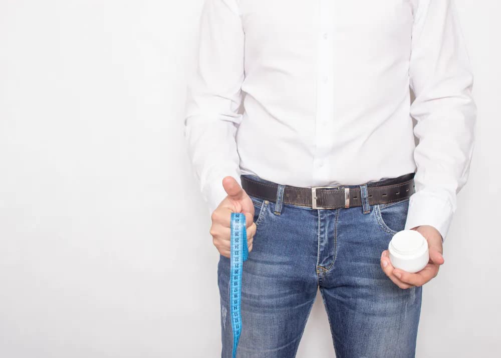 A man stood with a tape measure and a cream in his hands