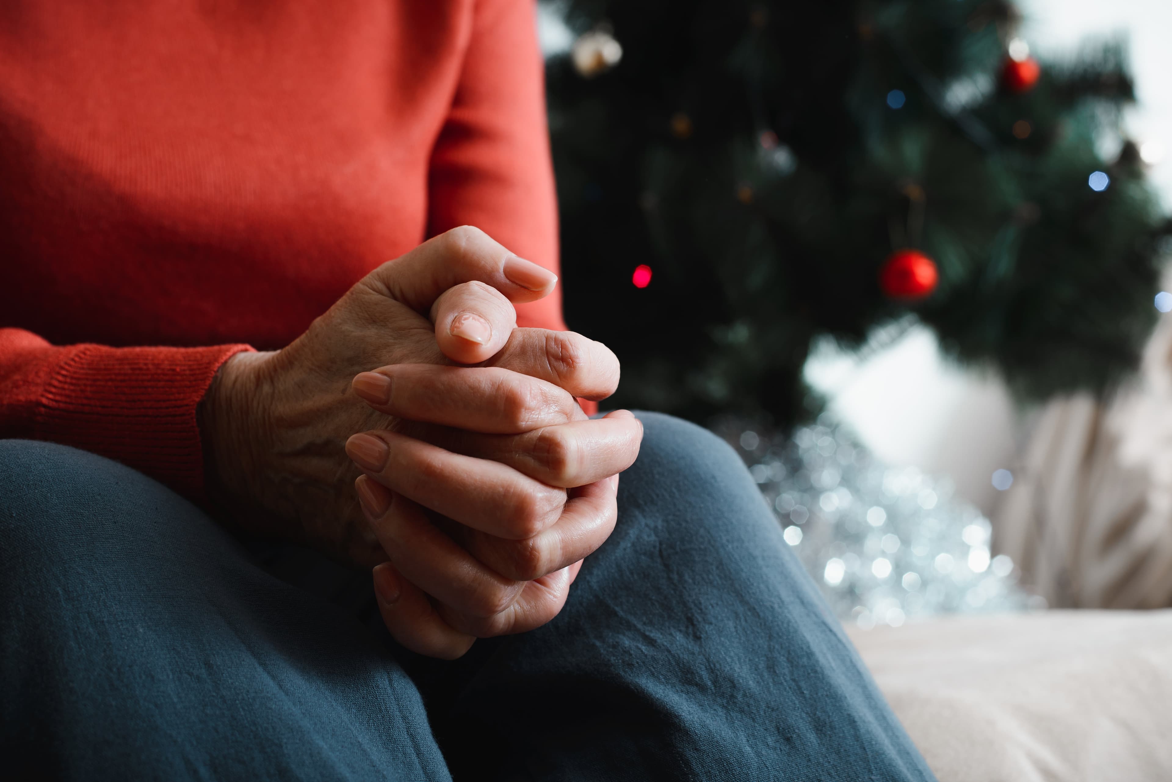A man sat in a withdrawn position in front of a Christmas tree